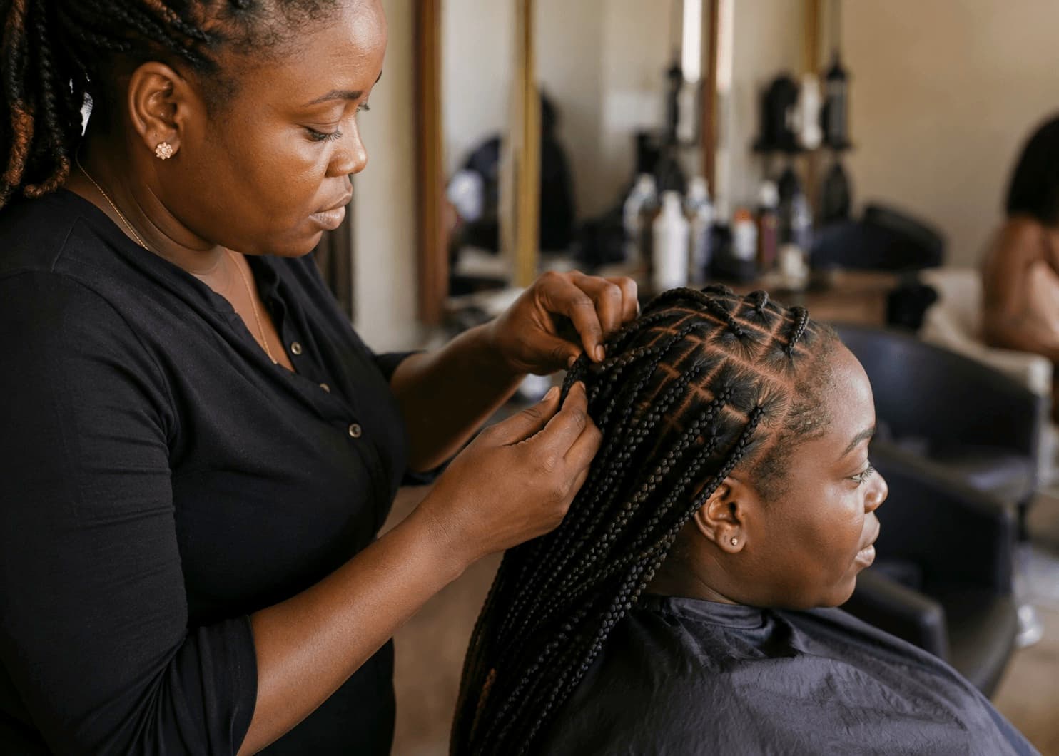 Coiffeuse tressant une cliente dans un salon à Abidjan